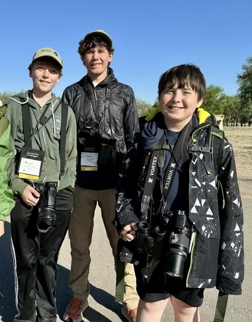 Photo of three teen boys with binoculars and cameras. 